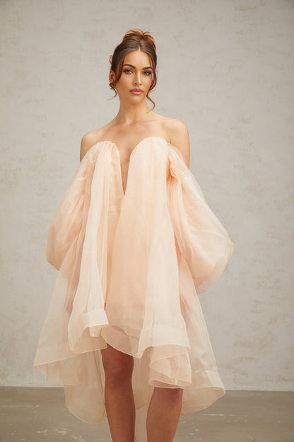 A short pink mini dress with voluminous sleeves and a large bow detail at the front neckline
