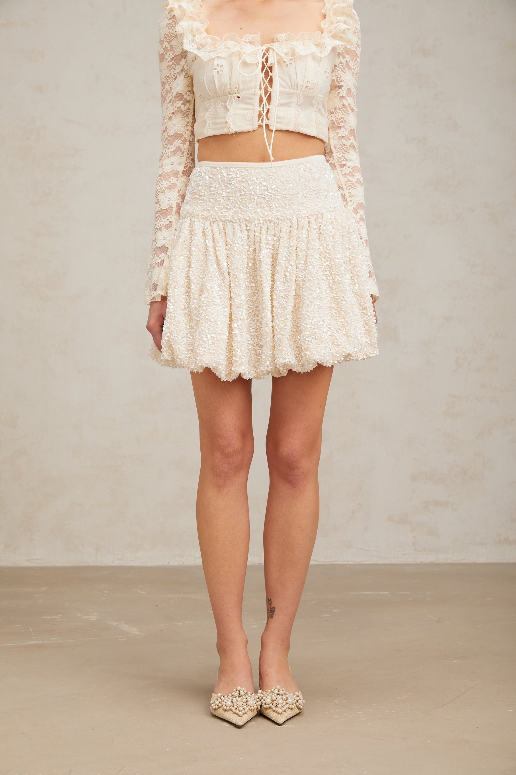 A short pleated mini skirt with sequin embellishments called Tiphaine