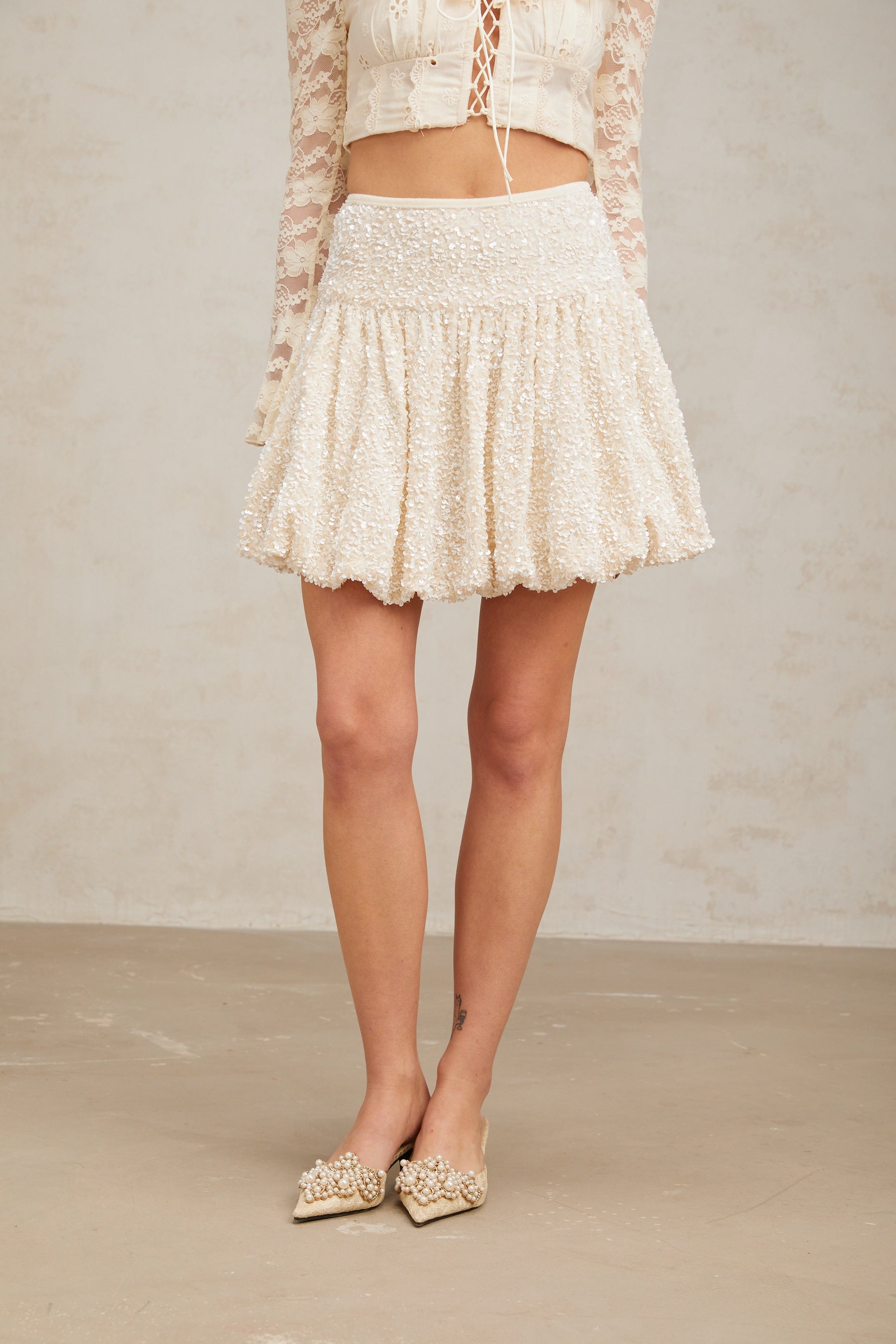 A short pleated mini skirt with shimmering sequins covering the fabric creating a sparkling effect