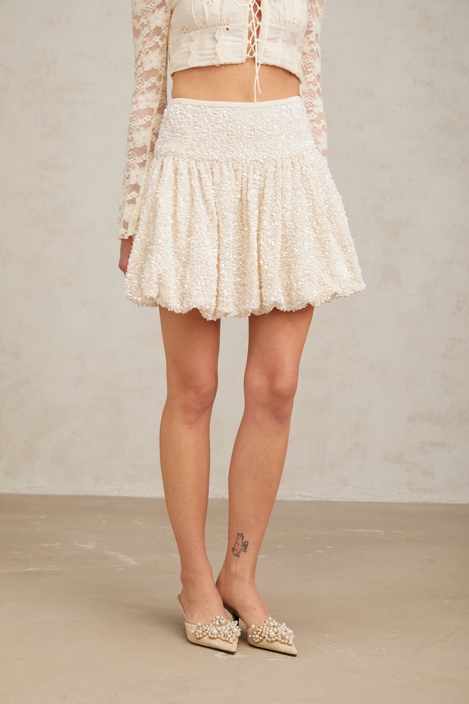 A short pleated mini skirt with shimmering sequins covering the fabric creating a sparkly and festive look
