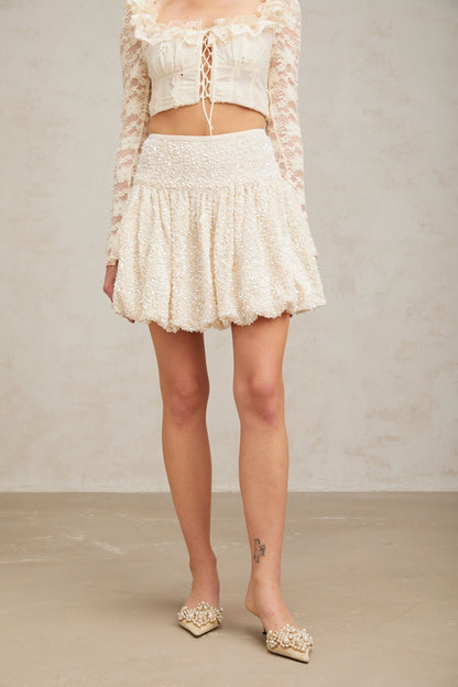 A short pleated mini skirt with shimmering sequins covering the fabric likely in a festive or glamorous style