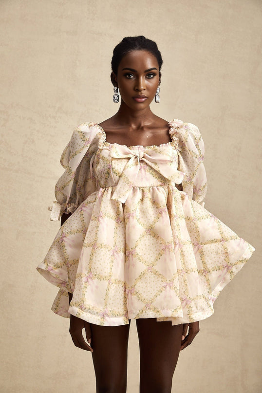 A short puffy mini dress with a check pattern featuring a large bow detail at the front in a playful and feminine style