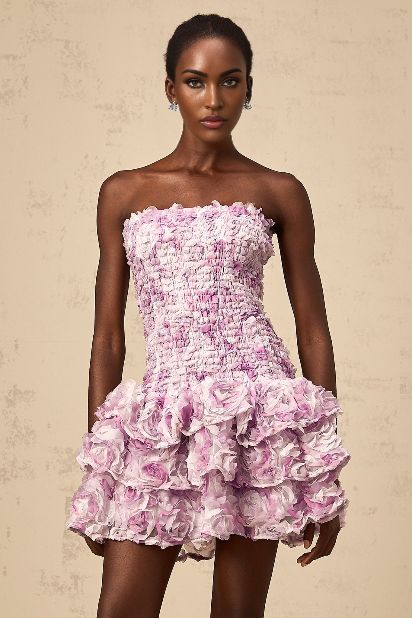 A short purple mini dress with multiple tiers of tulle fabric featuring three dimensional petal details throughout the skirt