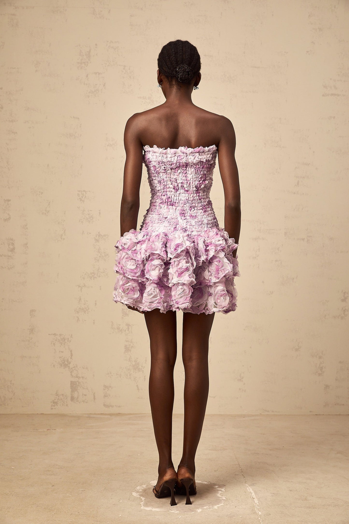 A short purple mini dress with tiered layers of tulle fabric featuring threedimensional petal details throughout creating a textured floral effect