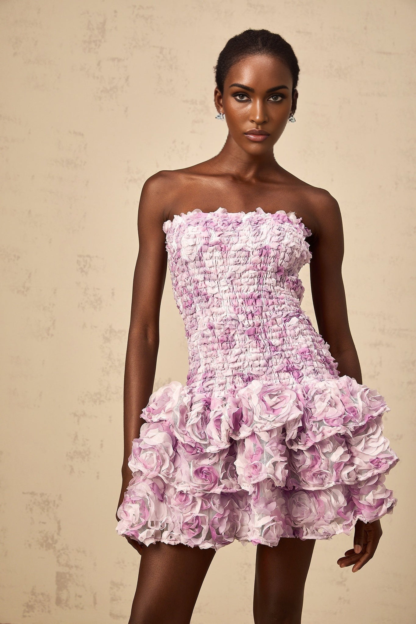 A short purple tulle mini dress with tiered layers featuring three dimensional petal details throughout creating a textured floral effect