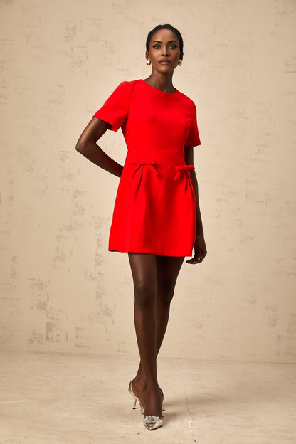 A short red mini dress with short sleeves and a bow detail featuring a feminine and playful design