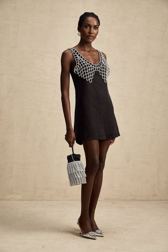 A short satin mini dress in a light color embellished with crystal details featuring a fitted silhouette and delicate straps