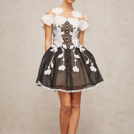 A short sleeveless dress with a colorblocked design featuring floral embroidery details in contrasting colors on a light background