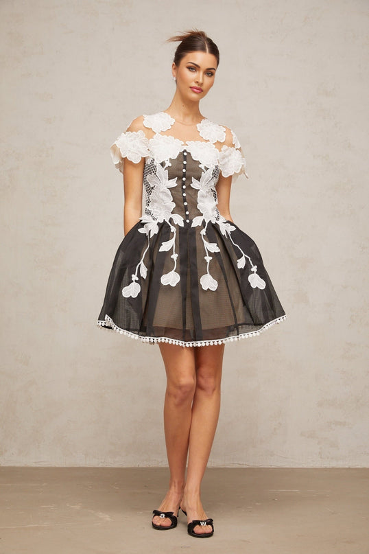 A short sleeveless dress with a colorblocked design featuring floral embroidery details in contrasting colors on a light background