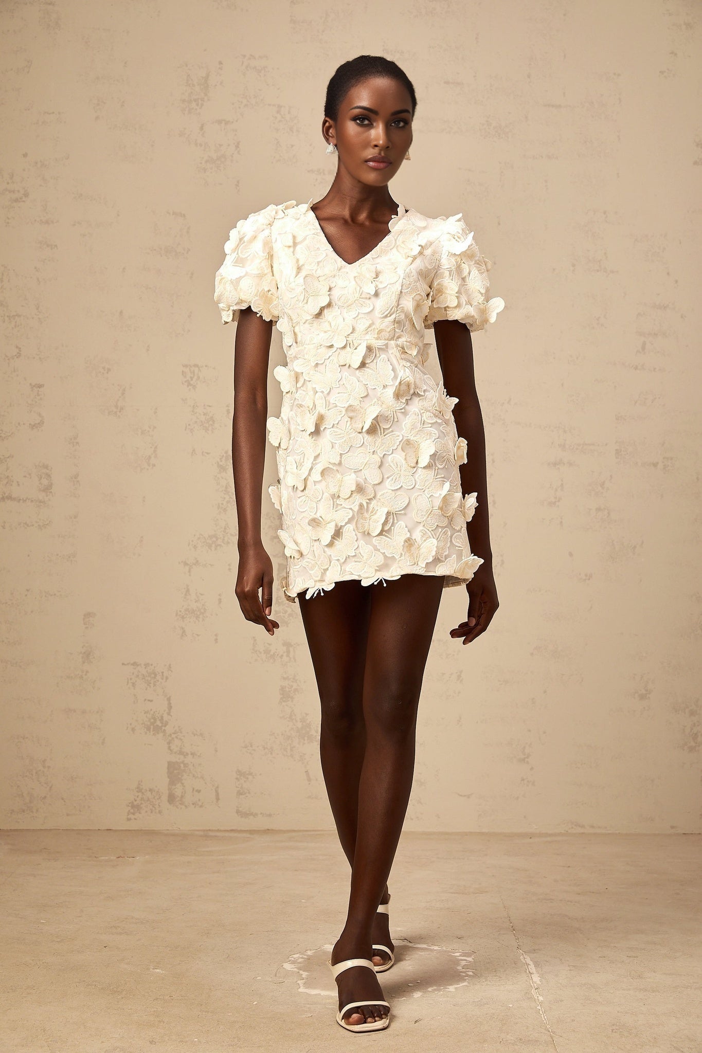 A short sleeveless dress with a flared Aline silhouette featuring colorful butterfly appliques scattered across the fabric