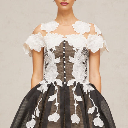 A short sleeveless dress with colorblocked sections and floral embroidery details featuring a mini length and feminine silhouette