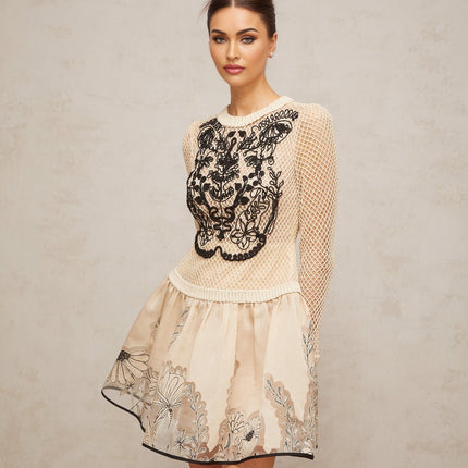 A short sleeveless mini dress with a floral jacquard pattern featuring contrasting color floral appliques and a fitted silhouette