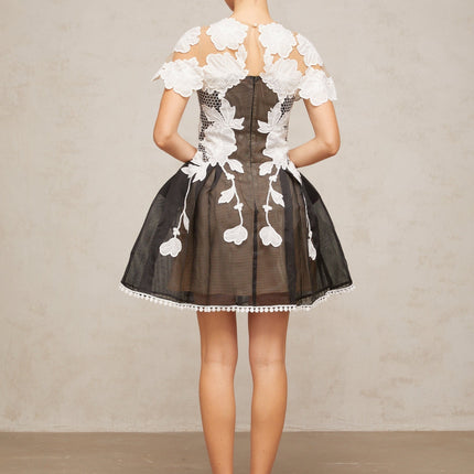 A short sleeveless mini dress with colorblocked sections featuring floral embroidery designs in contrasting colors creating a vibrant and feminine look