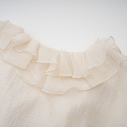 A short tiered mini dress in neutral tones featuring floral applique details and a delicate Zephyrine design