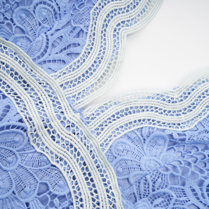 A short white dress with floral embroidery and a Vneckline on a female model