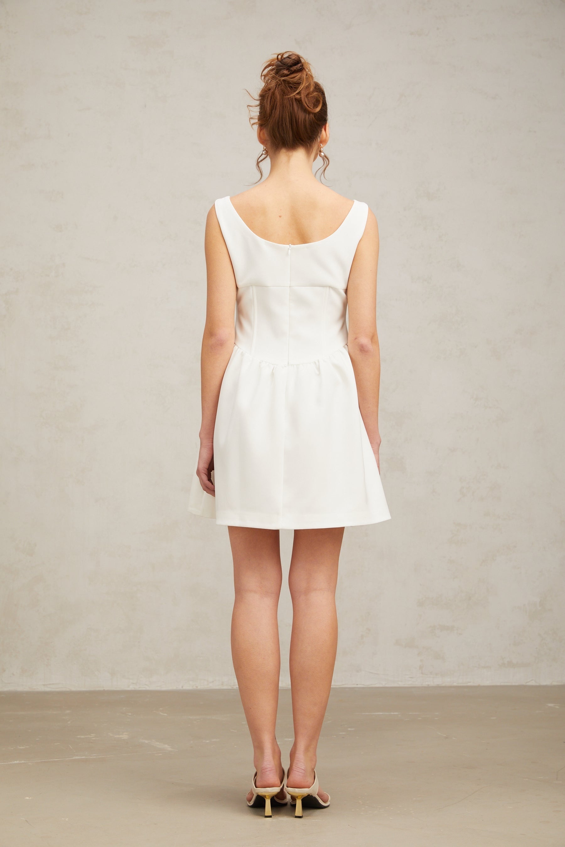 A short white mini dress adorned with crystal embellishments featuring a fitted silhouette and shimmering details