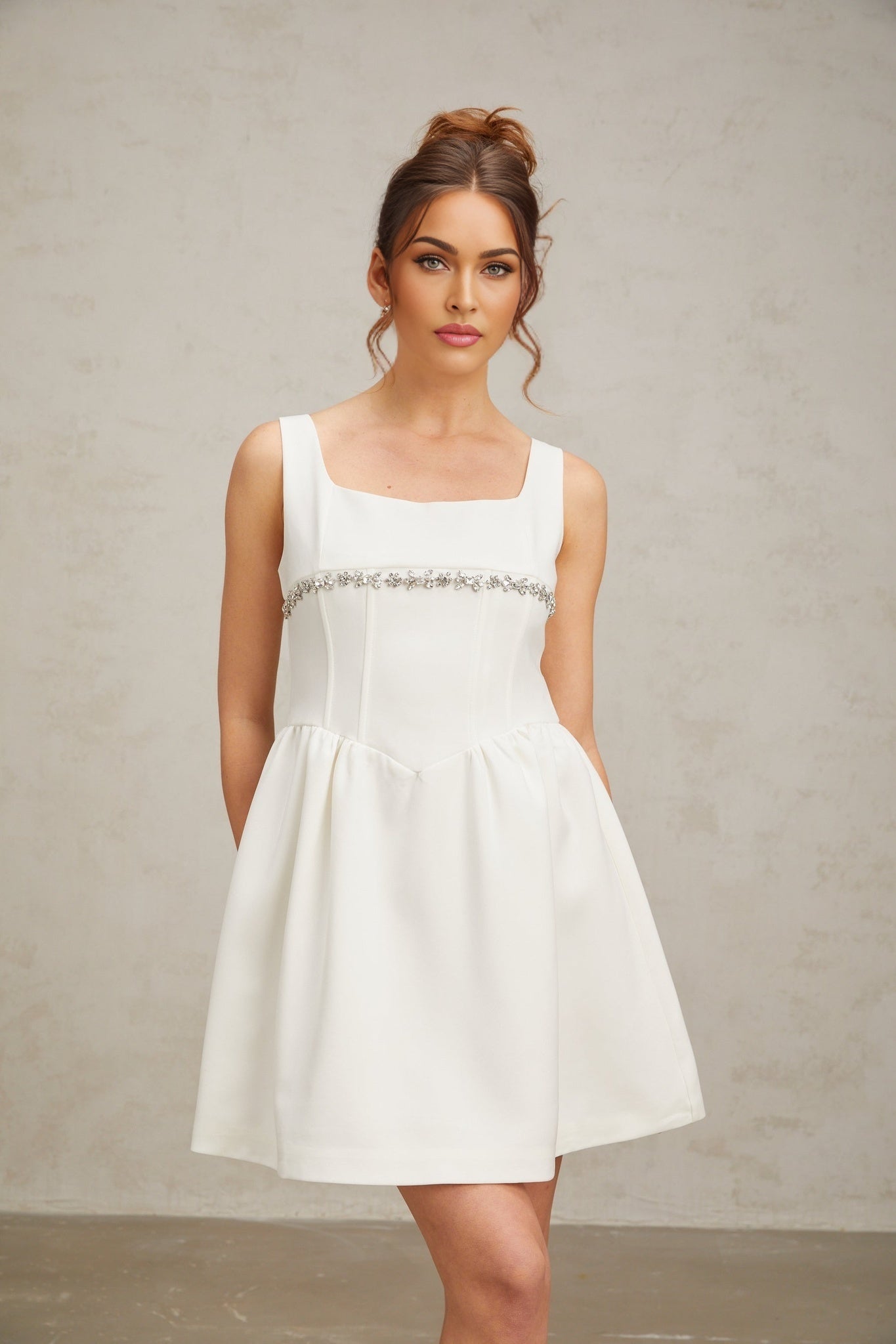 A short white mini dress adorned with crystal embellishments featuring a sleek and elegant design suitable for formal occasions
