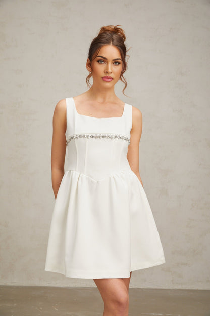 A short white mini dress adorned with crystal embellishments featuring a sleek and elegant design suitable for formal occasions