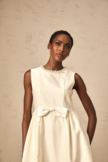 A short white mini dress with a bow accent featuring a fitted silhouette and named Isabelle