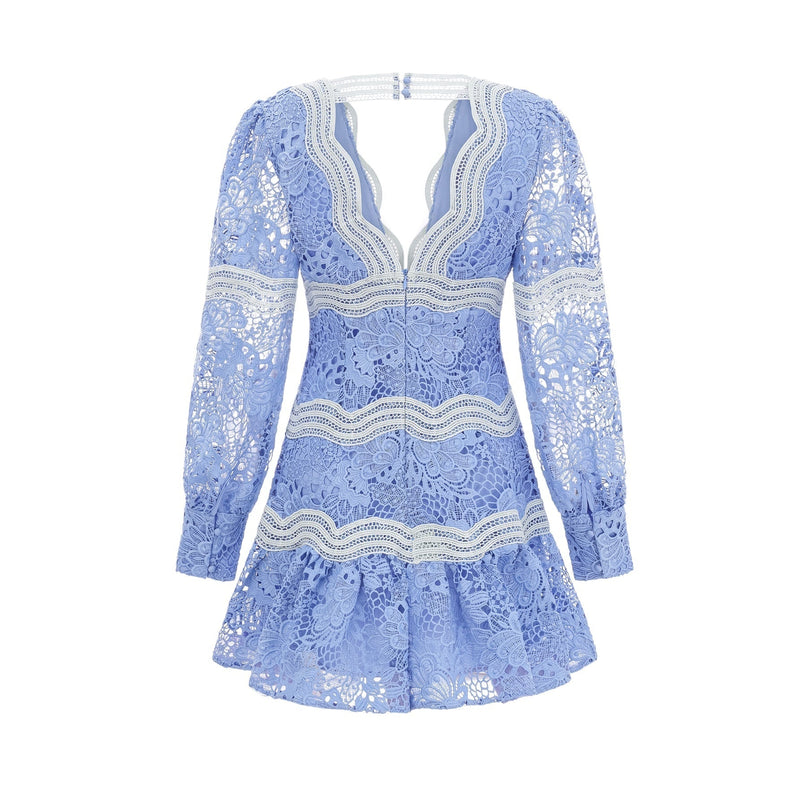 A short white mini dress with a Vneck and colorful floral embroidery details worn by a model standing against a plain background