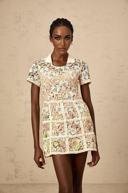 A short white mini dress with colorful floral embroidery featuring a fitted bodice and flared skirt
