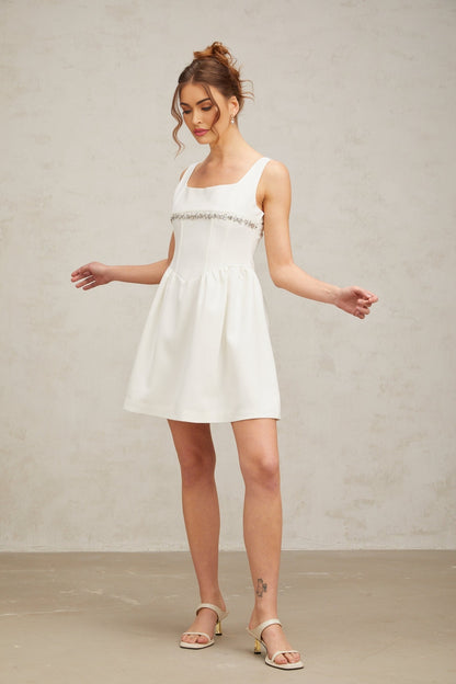 A short white mini dress with crystal embellishments adorning the fabric named Flavia