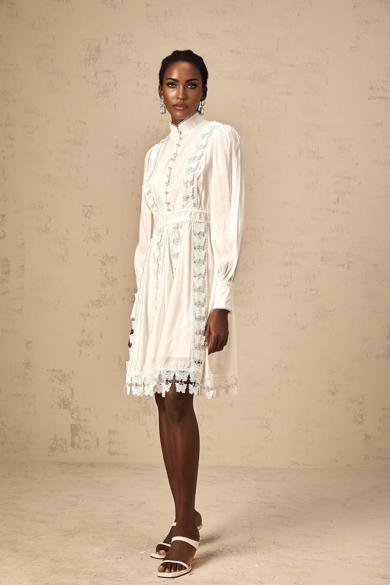 A short white mini dress with decorative butterfly appliques on the fabric