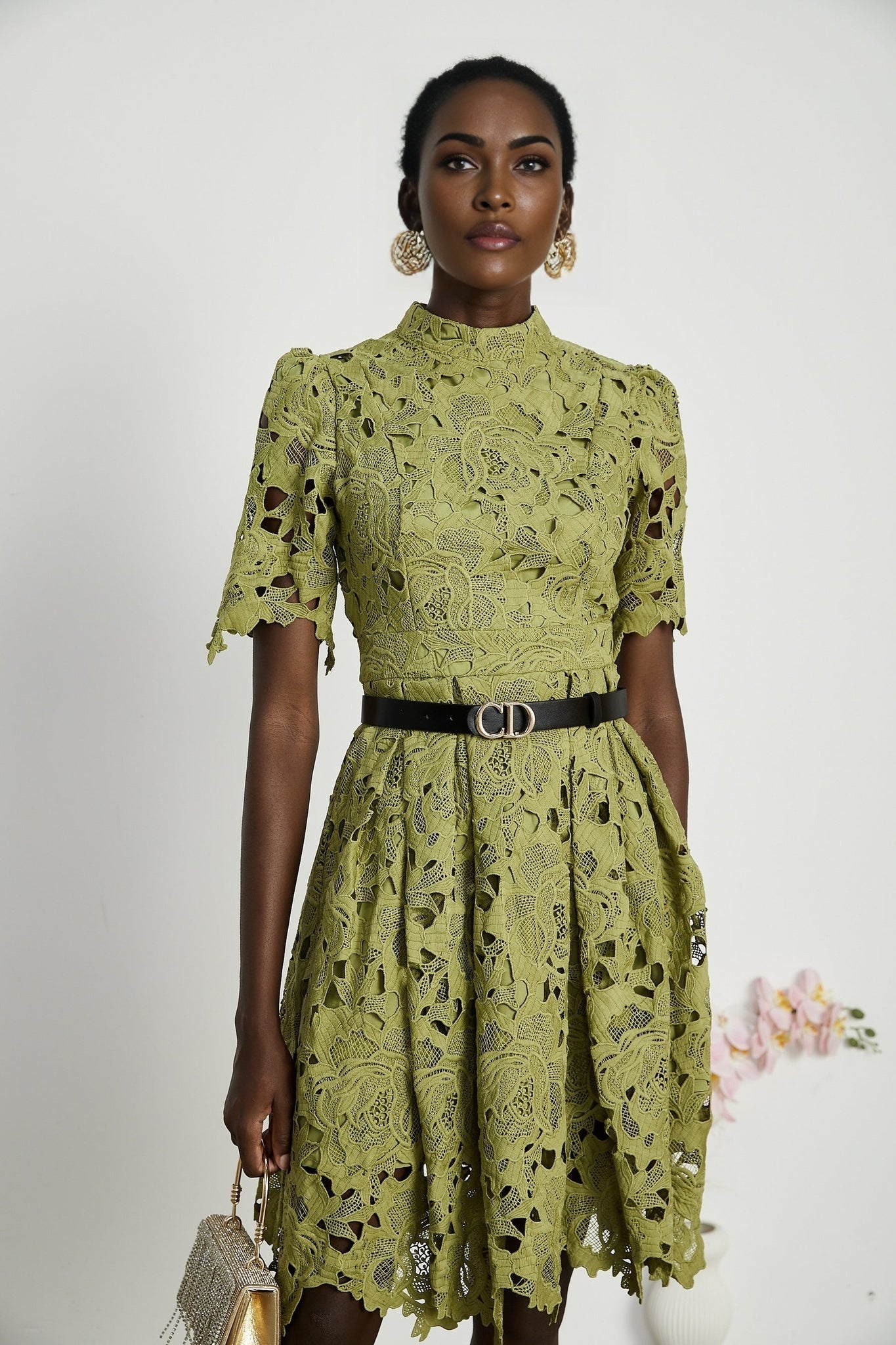 A short white mini dress with embroidery details and strategic cut out sections worn by a model against a plain background