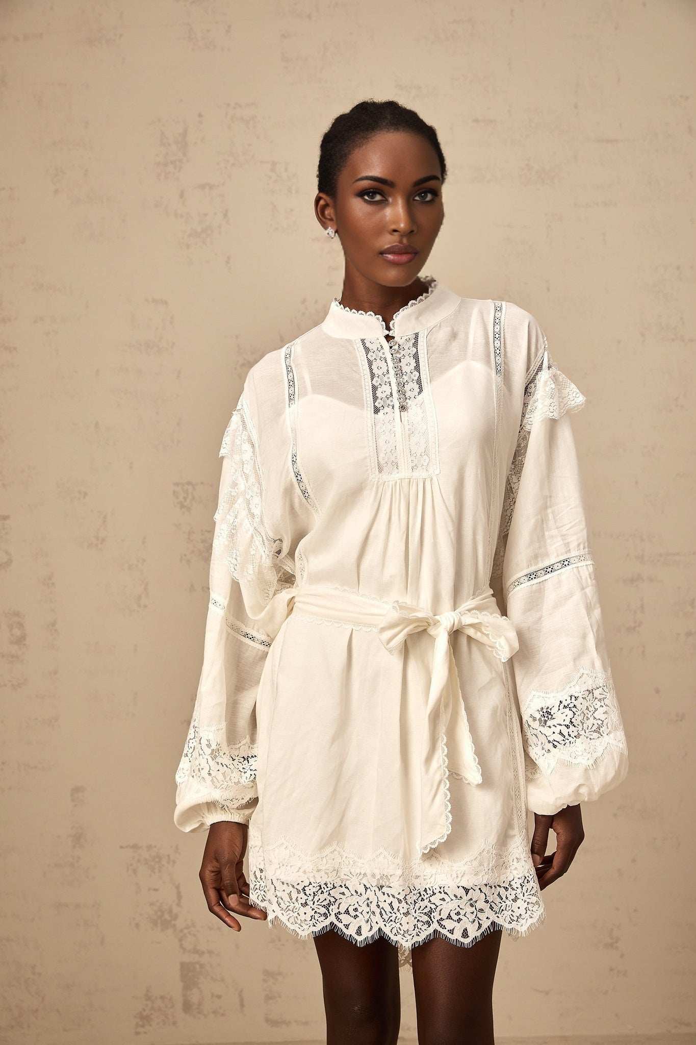 A short white mini dress with floral lace trim details shown on a model against a plain background