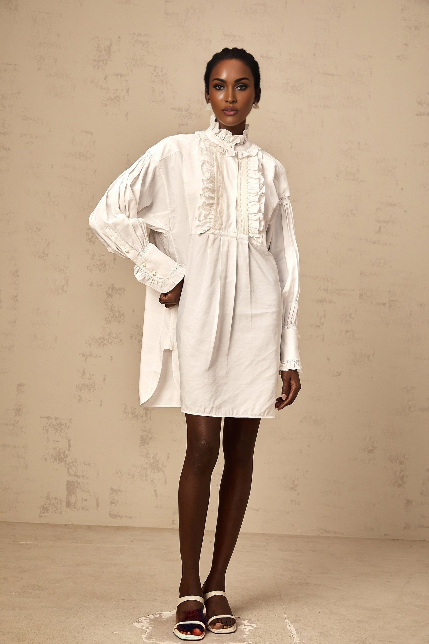 A short white mini dress with lace trim and ruffled details featuring a shirtstyle design and delicate feminine look