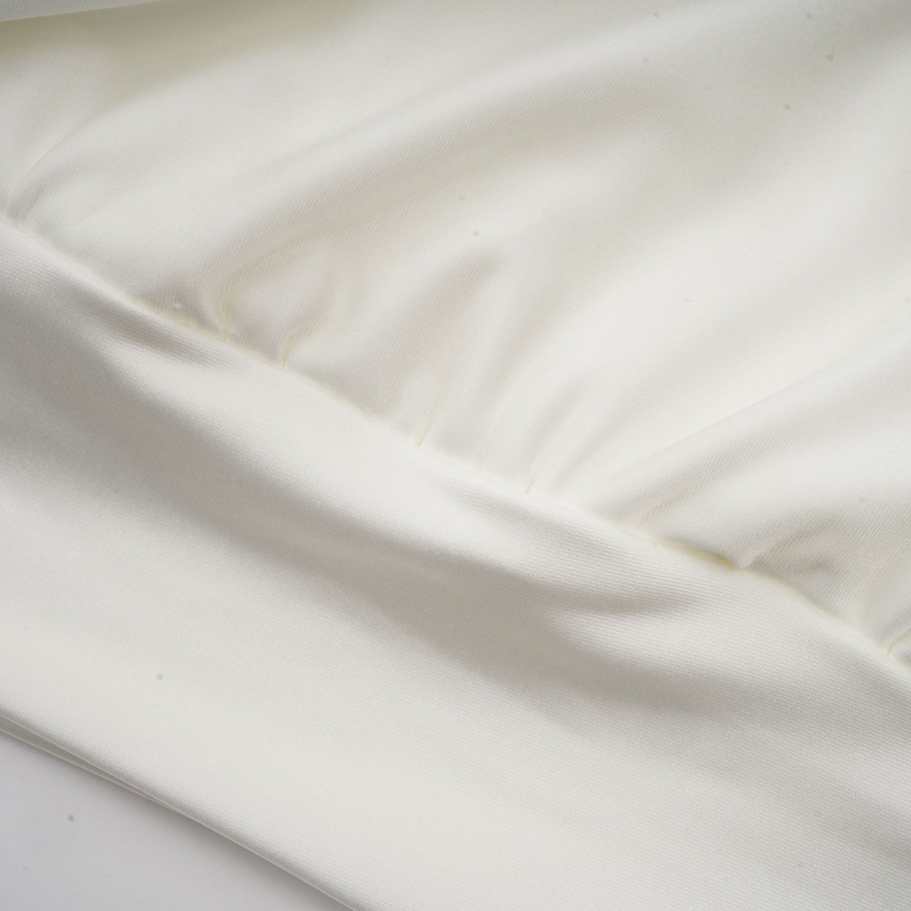A short white mini dress with ruched detailing and faux flower embellishments