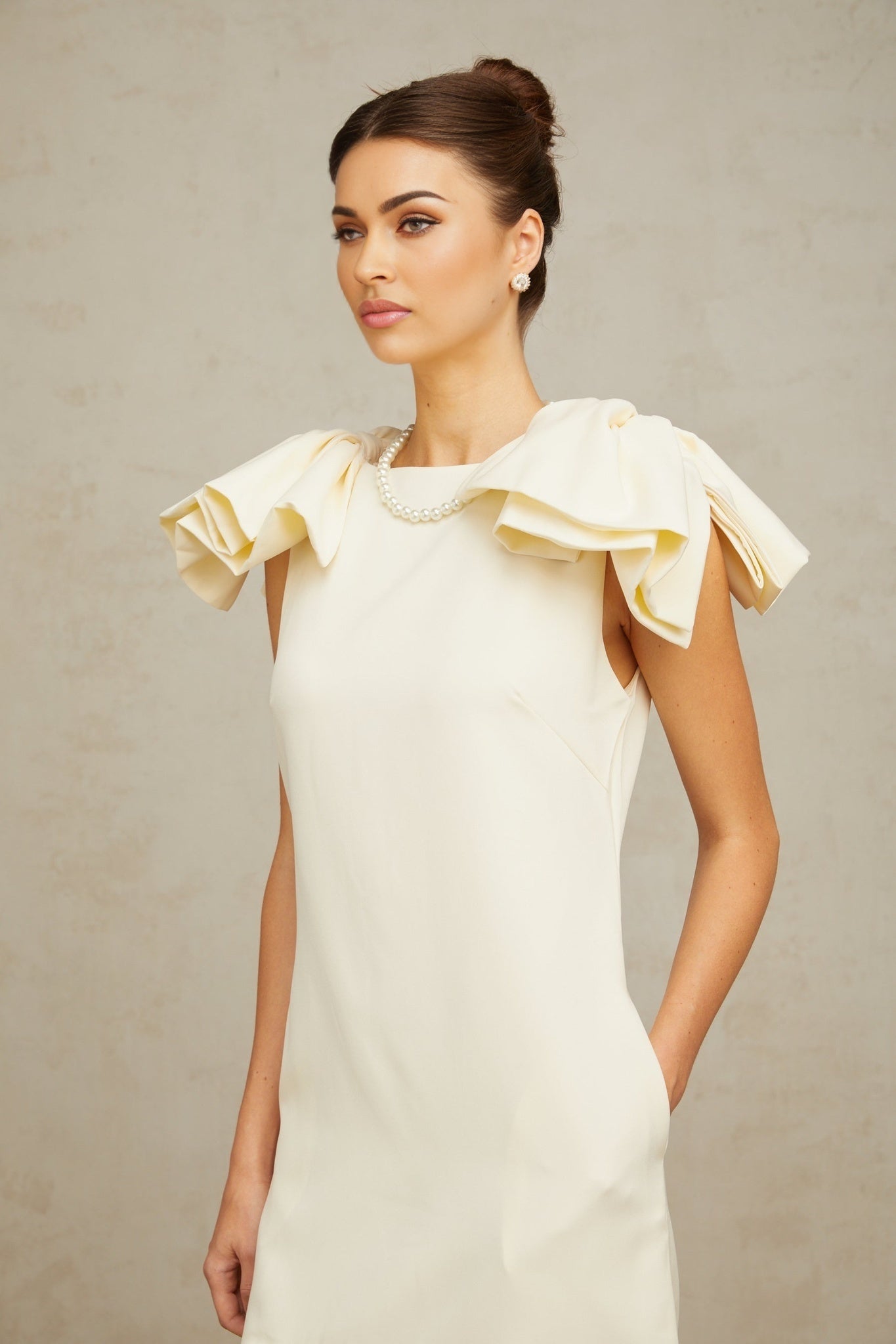 A short white mini dress with ruffled details and a prominent bow accent