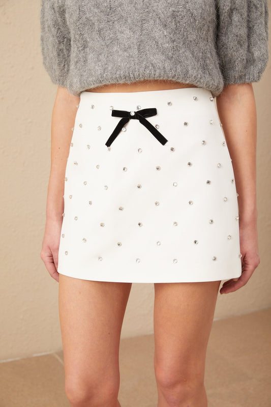 A short white mini skirt with a crystalembellished bowknot detail at the waist