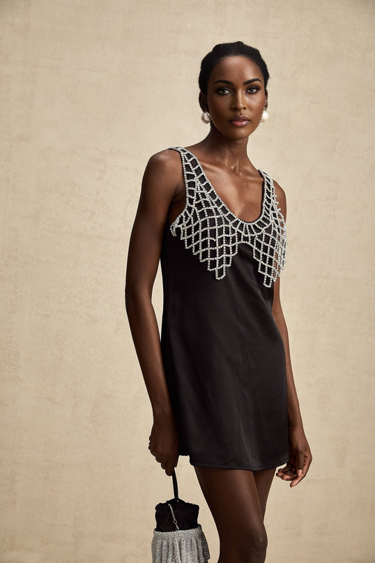 A short white satin mini dress adorned with sparkling crystal embellishments featuring a sleek silhouette and elegant design