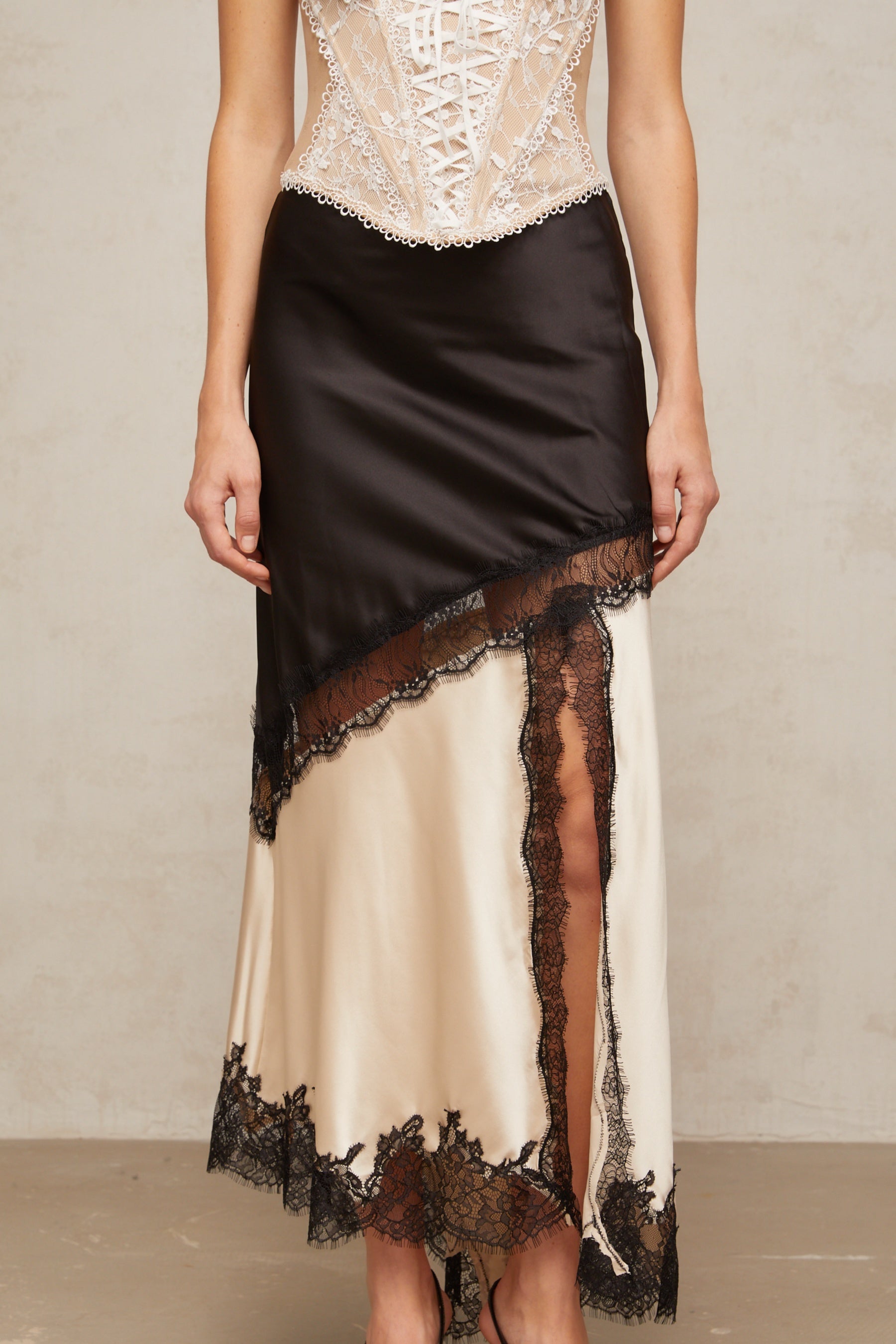 A sleek asymmetric satin skirt with delicate lace panel detailing named Raphaelle featuring a flowing silhouette and elegant design