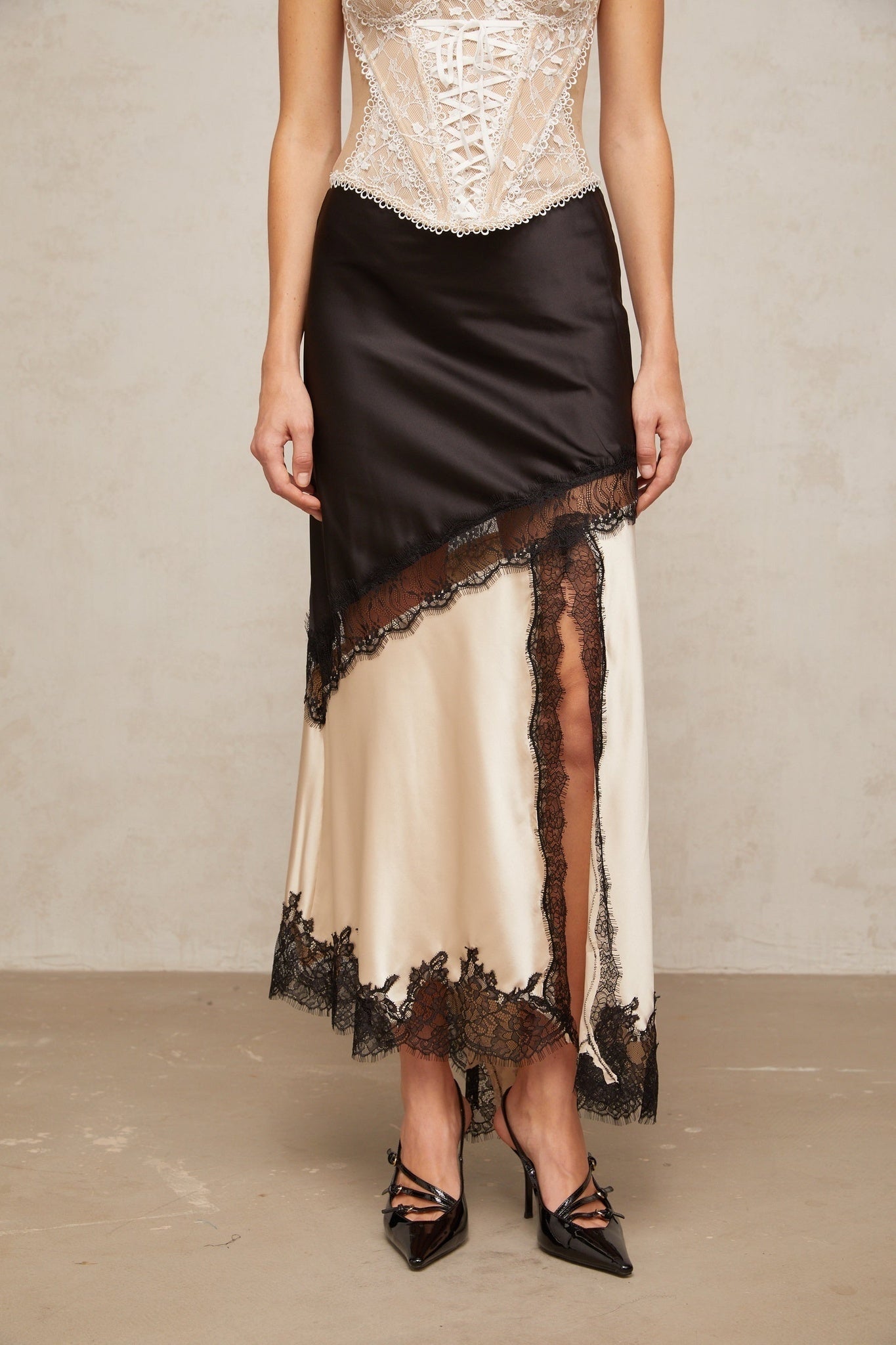 A sleek satin skirt with an asymmetric hemline featuring delicate lace panels and a feminine silhouette named Raphaelle