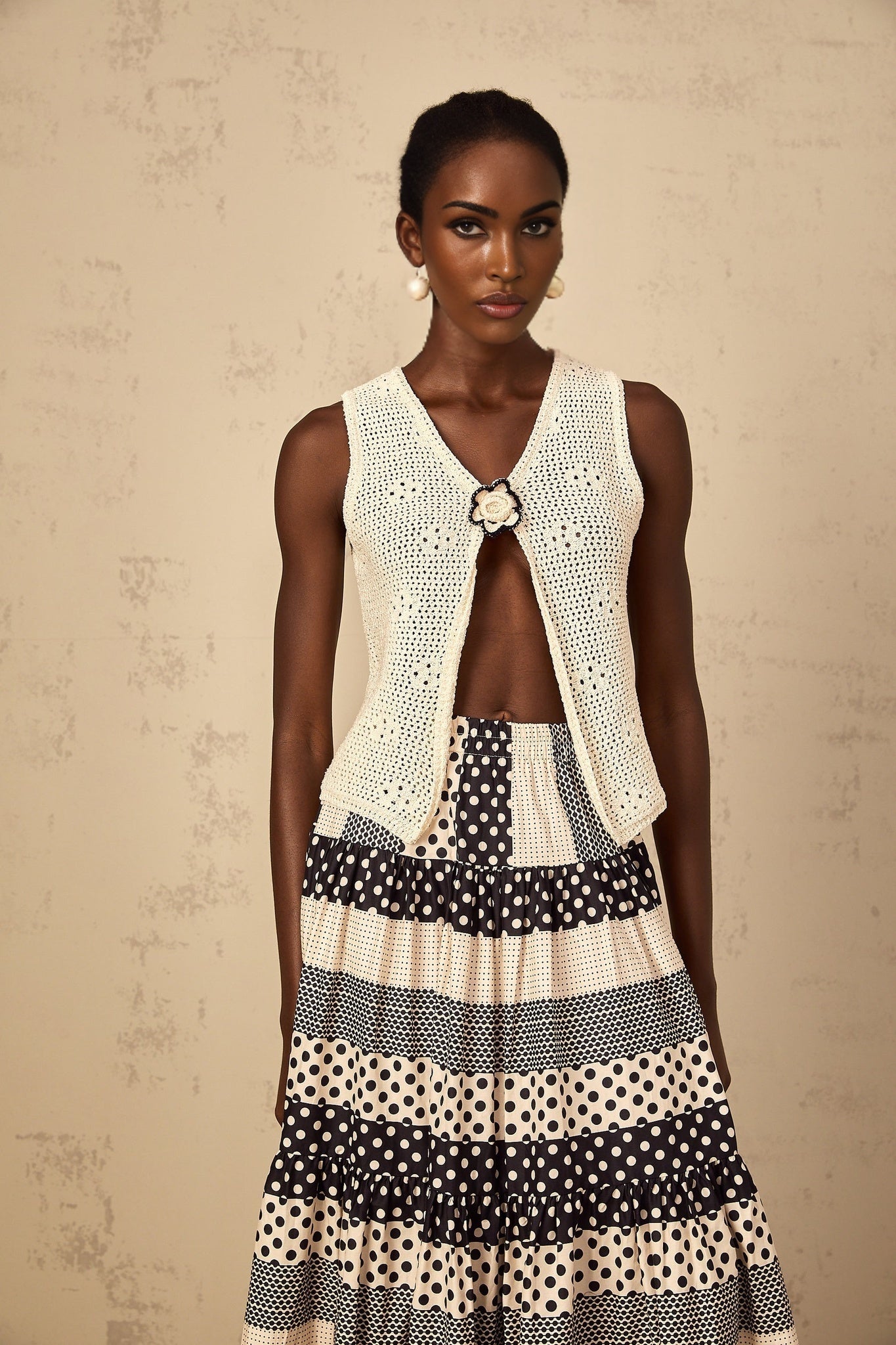 A sleeveless crochet knit tank top in an open front style with a delicate pattern and loose weave