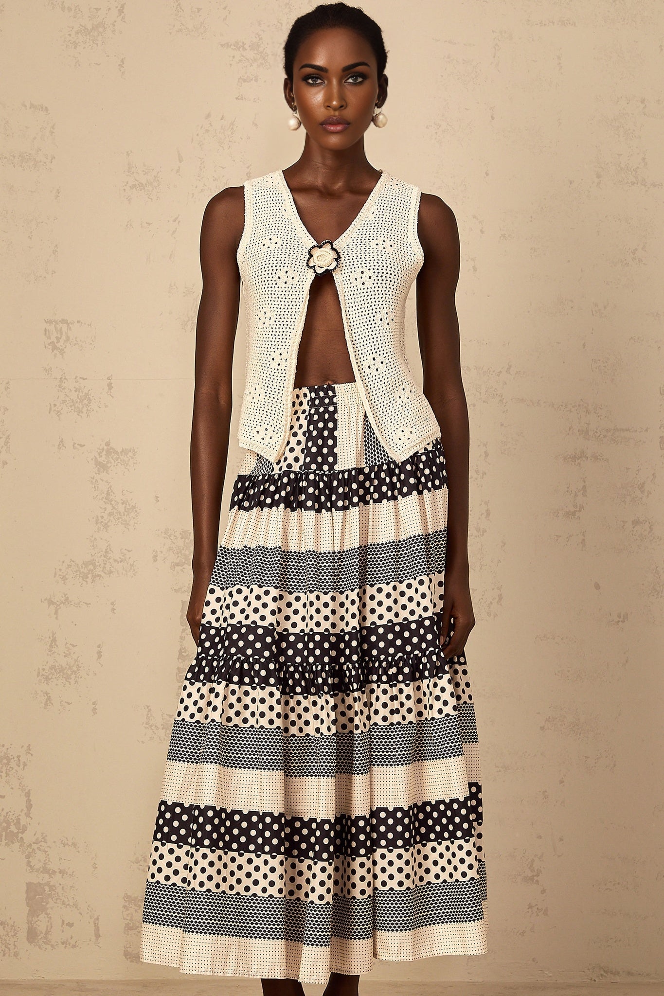 A sleeveless crochet knit tank top with an open front design featuring a delicate floral pattern in white