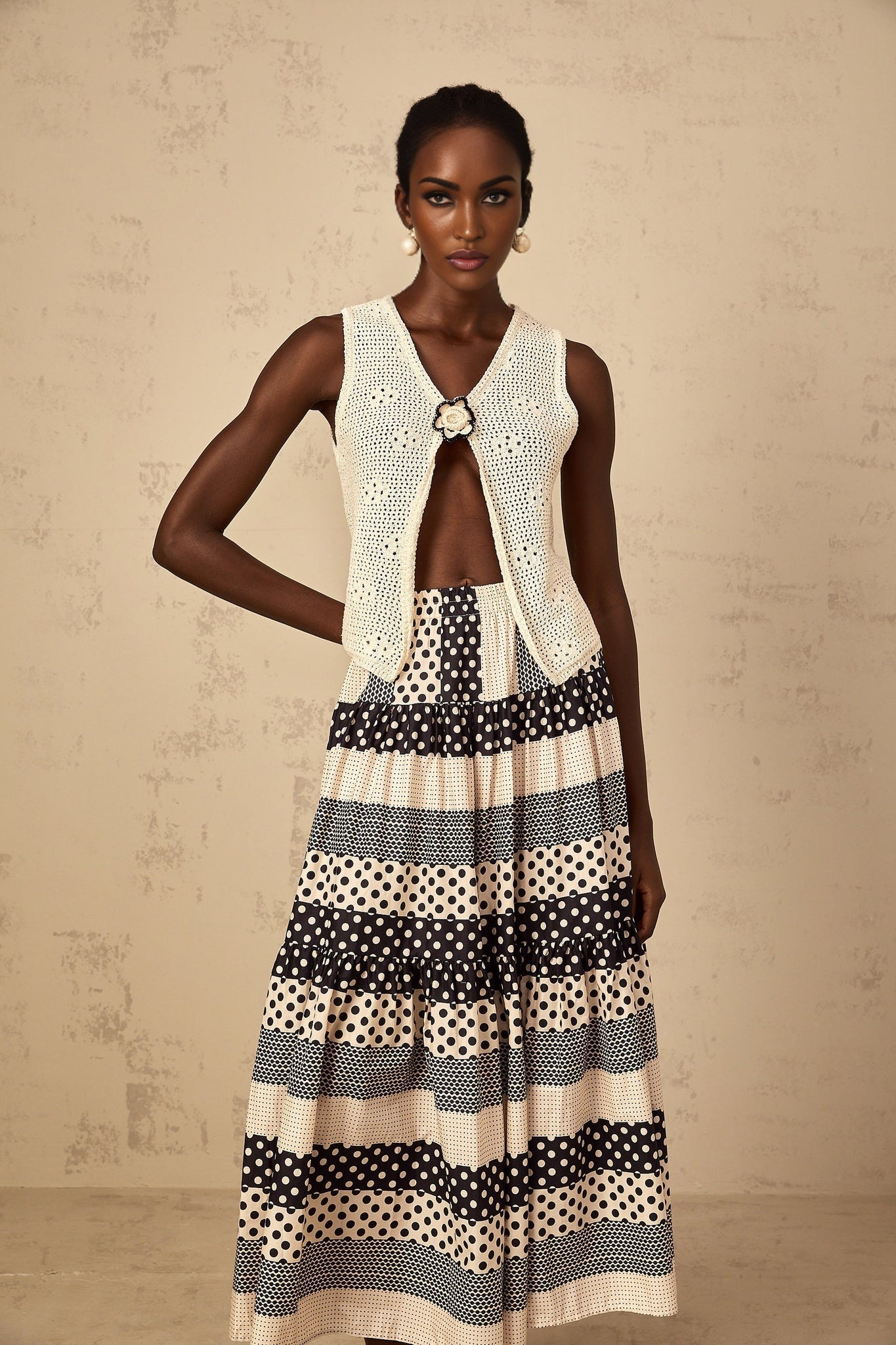 A sleeveless crochet knit tank top with an open front design in a light color featuring a delicate pattern and loose fit