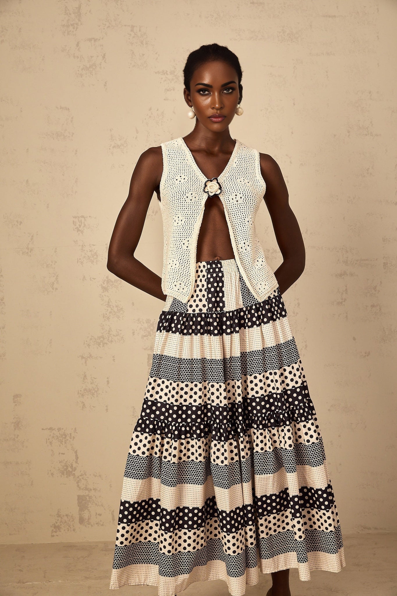 A sleeveless crochet knit tank top with an open front design in a light color featuring a delicate pattern and loose fit