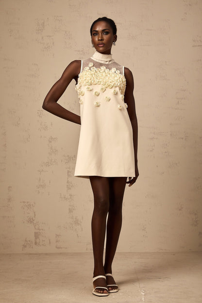 A sleeveless mini dress with floral pattern featuring faux flowers on a light background