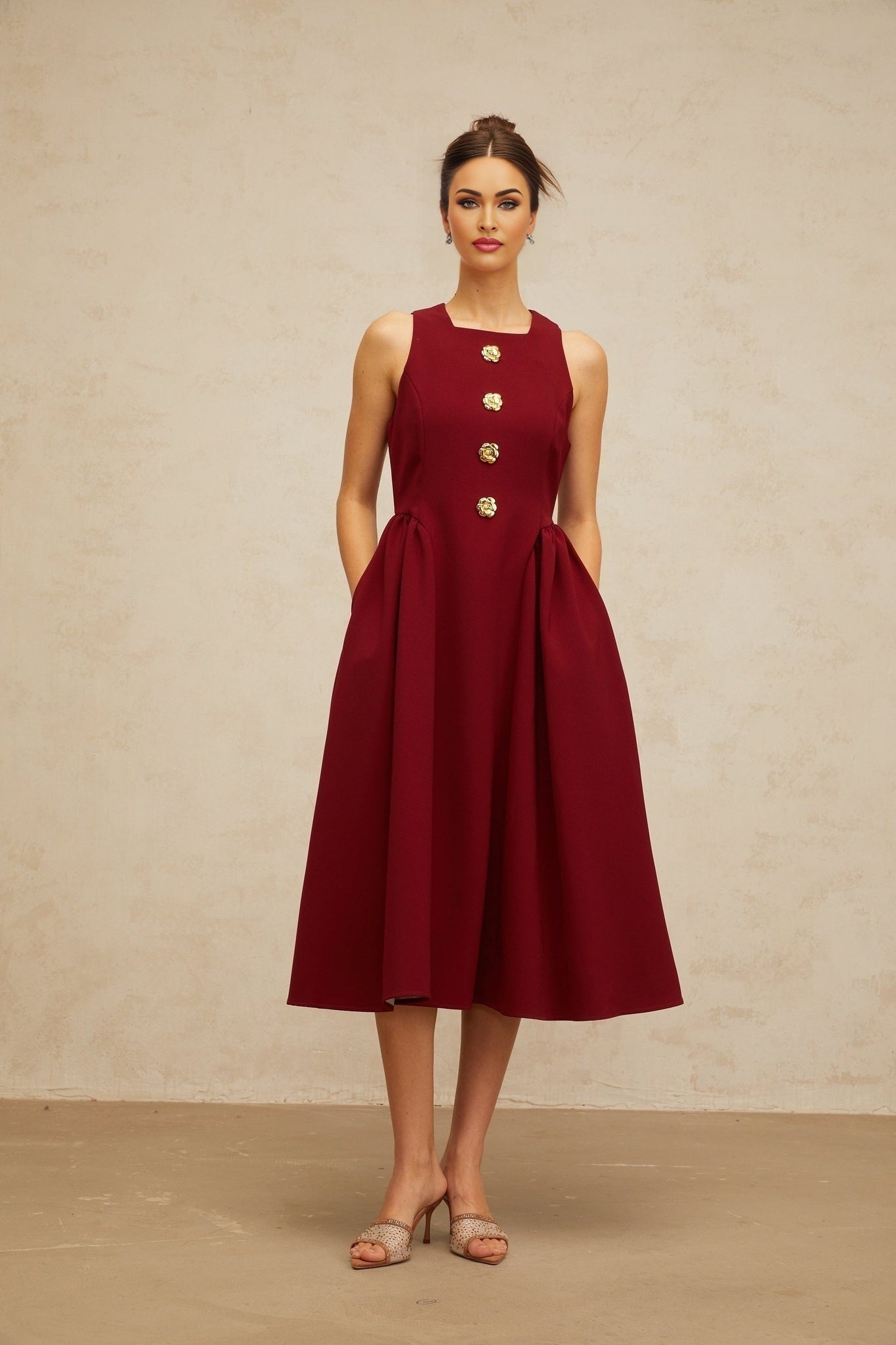 A sleeveless red midi dress with a pleated skirt and floral pattern featuring a tank top style bodice and a flowy silhouette