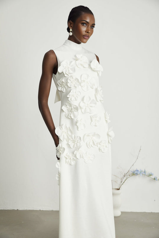 A sleeveless white maxi dress with a bow and decorative artificial flowers