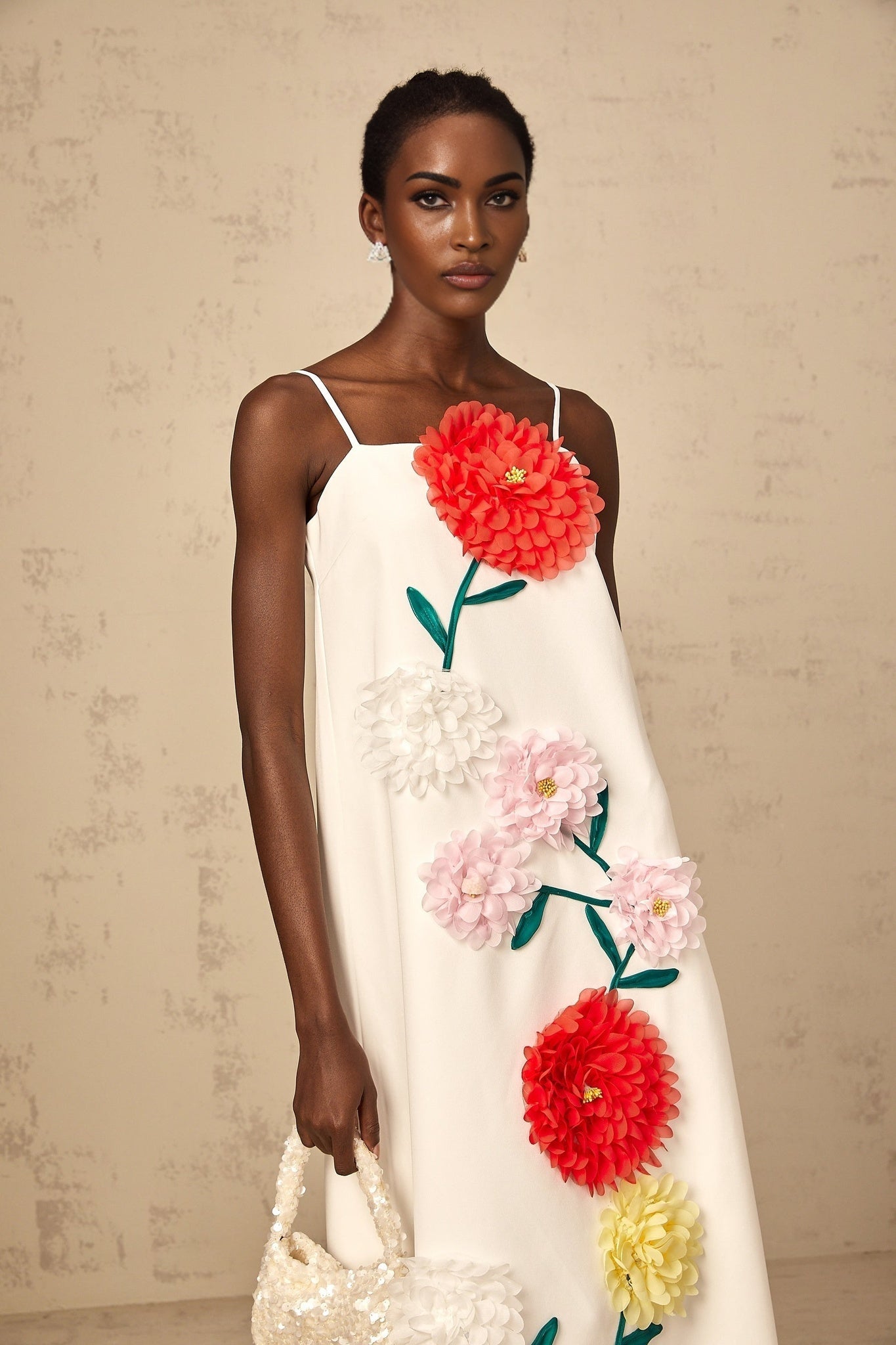 A sleeveless white midi dress with 3D petal details on the bodice featuring a fitted silhouette and floral inspired texture