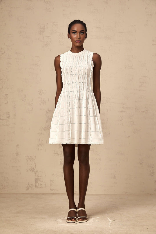 A sleeveless white mini dress with ruffled details and a knit fabric featuring a fitted silhouette and a short hemline
