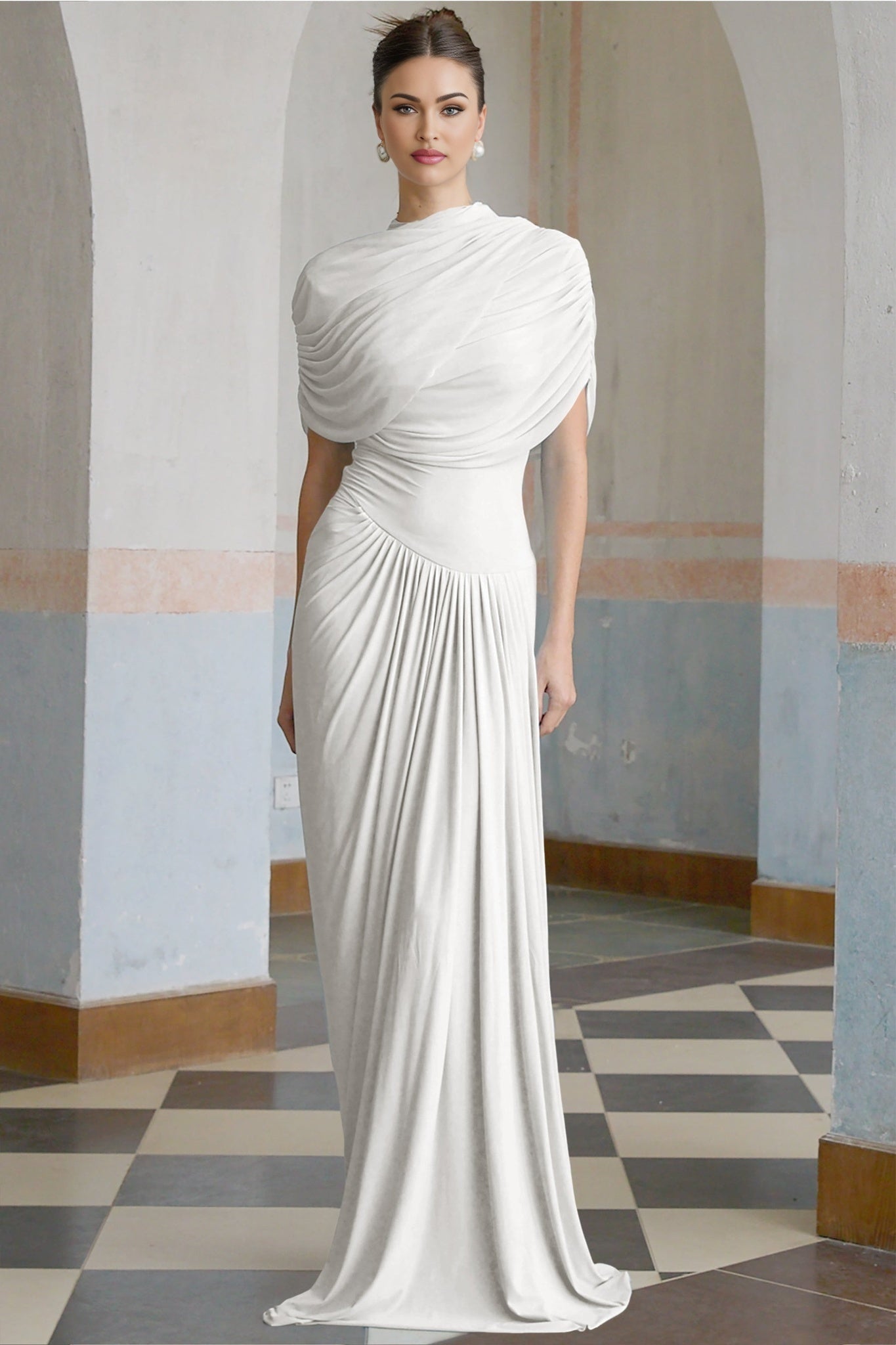 A white asymmetric maxi dress with pleated details and a long flowing skirt worn by a model
