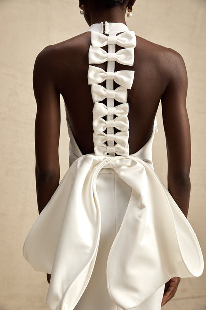 A white bandage dress with an oversized bow accent named Capucine featuring a formfitting silhouette and elegant design