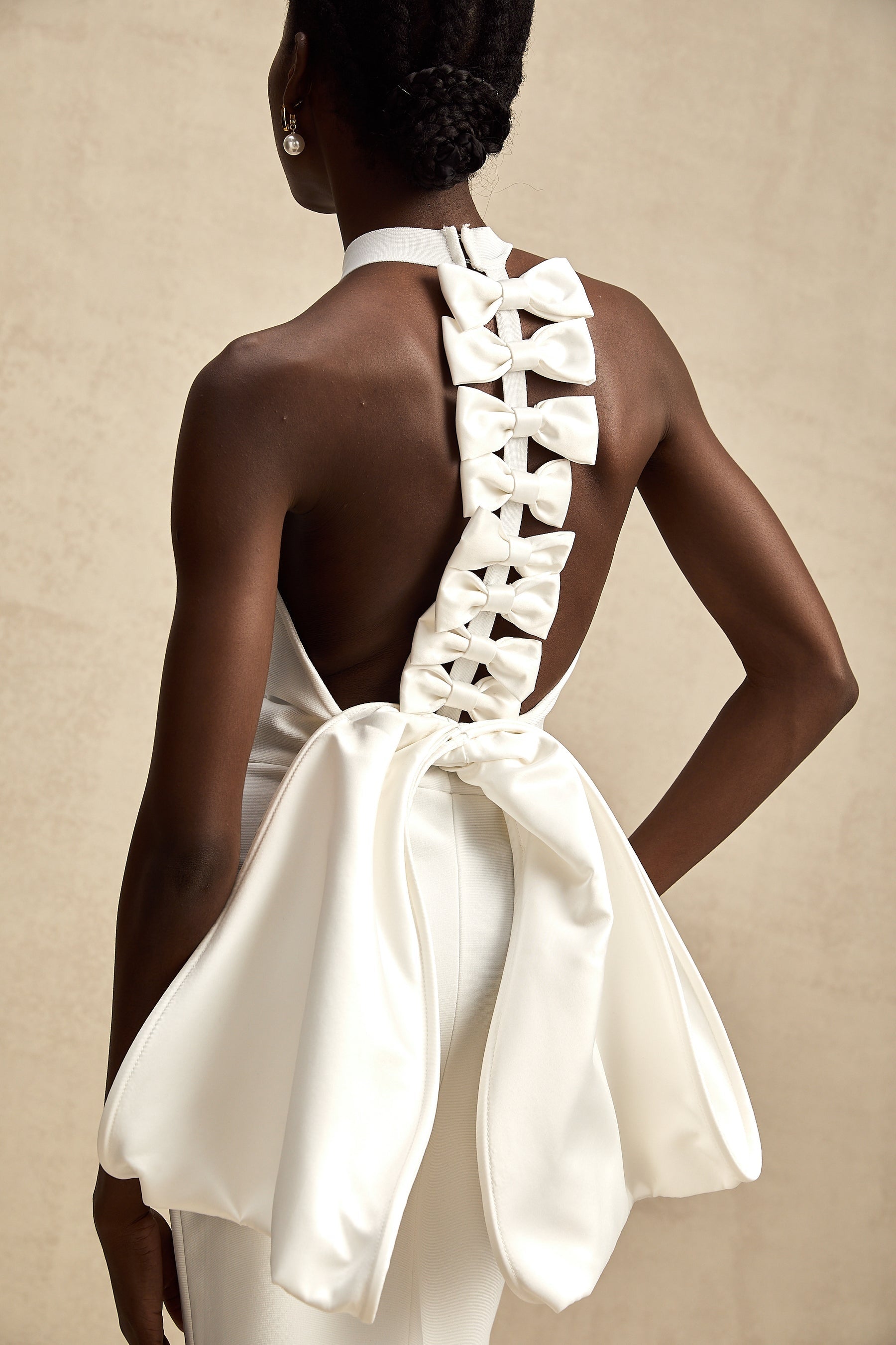 A white bandage dress with an oversized bow detail featuring a fitted silhouette and capucine style design