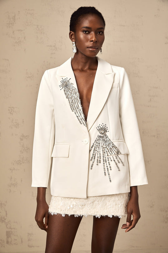 A white blazer adorned with crystal embellishments featuring a tailored fit and sparkly accents