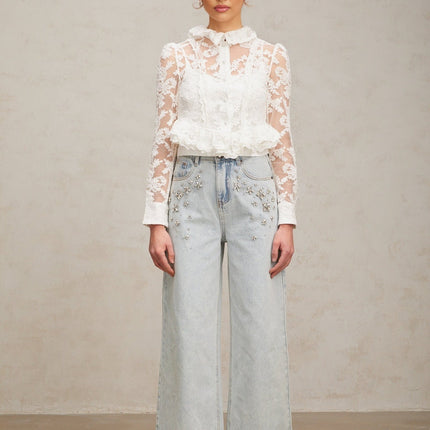 A white blouse with delicate floral embroidery and lace detailing named Karine